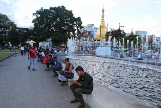 People access mobile data while relaxing in the Mahabandoola Park at the heart of Yangon/ Smartphone penetration is one of the main drivers of Myanmar's tech disruption. (Photo-Khine Kyaw, Myanmar Eleven)