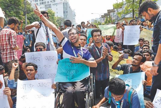  Daffodil University student Uzzal Bairagi in a wheelchair chanting slogans at a demonstration calling for safer roads on Dhanmondi 27 in the capital around noon yesterday. Similar protests have been taking place at different places in the city since a university student was run over and killed near Bashundhara area on Tuesday. Photo: Palash Khan