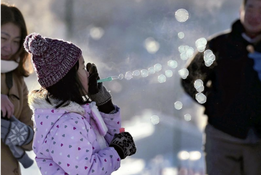A girl blows bubbles that freeze as soon as they form in Rikubetsu, Hokkaido, on Saturday morning, when temperatures fell to minus 30 C./The Japan News