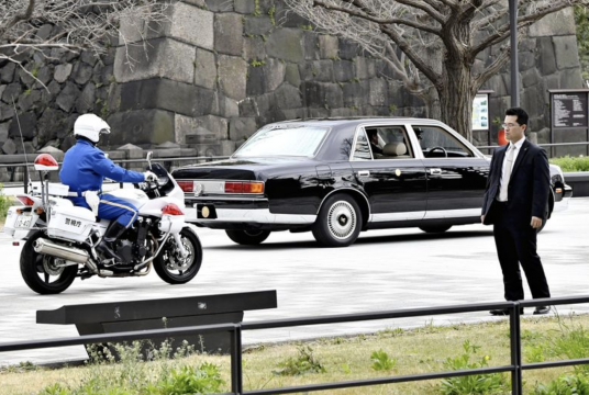 A policeman on a motorbike guards a car transporting the Emperor and Empress in Chiyoda Ward, Tokyo, on March 28./The Japan News file photo