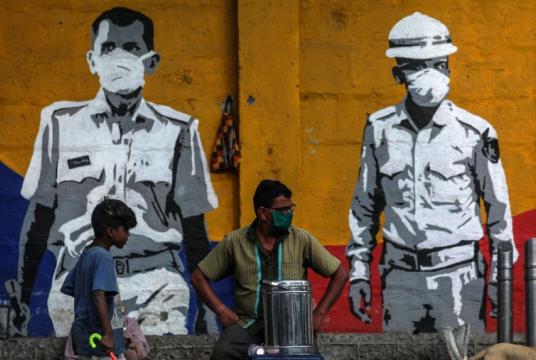 People sit in front of a wall honouring frontline workers in the fight against coronavirus, in Mumbai, India.PHOTO: EPA-EFE