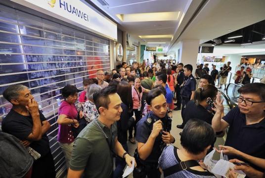 A crowd (above) outside the Huawei store at Nex mall last Friday. Police had to be called in at many outlets to manage the angry crowds. PHOTOS: GAVIN FOO, REUTERS