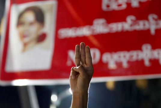 A man flashes a three-finger salute near a portrait of Aung San Suu Kyi to show his resistance against the military coup in Yangon, Feb 4, 2021.PHOTO: EPA-EFE