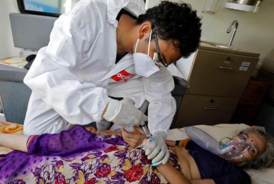 A doctor tends to a patient with a breathing problem inside an ambulance waiting to enter a COVID-19 hospital for treatment, amidst the spread of the coronavirus disease (COVID-19) in Ahmedabad, India, April 25, 2021. Photo: Reuters/Amit Dave