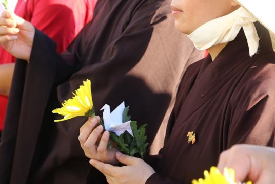 Each delegate at the memorial ceremony holds a flower and an origami bird to offer