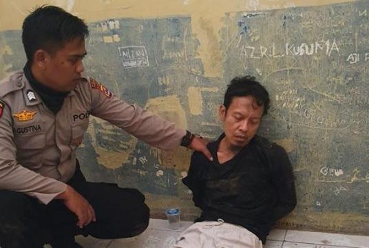A police officer holds Syahrial Alamsyah at Menes town square in Pandeglang, Banten after Syahrial allegedly attacked Coordinating Political, Legal and Security Affairs Minister Wiranto on Thursday. (Tempo.co/Istimewa)