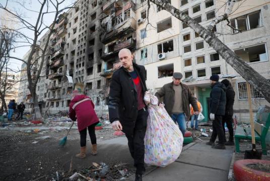Men carry belongings as they leave a destroyed home after shelling in Kyiv on March 14, 2022. PHOTO: EPA-EFE