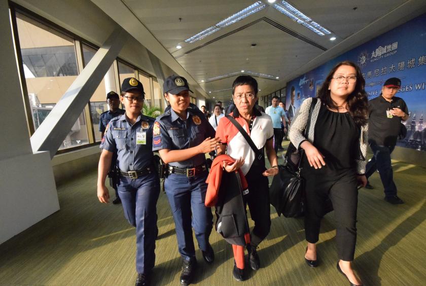 Philippine journalist Maria Ressa (2nd R), is escorted by police after an arrest warrant was served, shortly after arriving at the international airport in Manila on March 29, 2019. (Photo by STR / AFP)