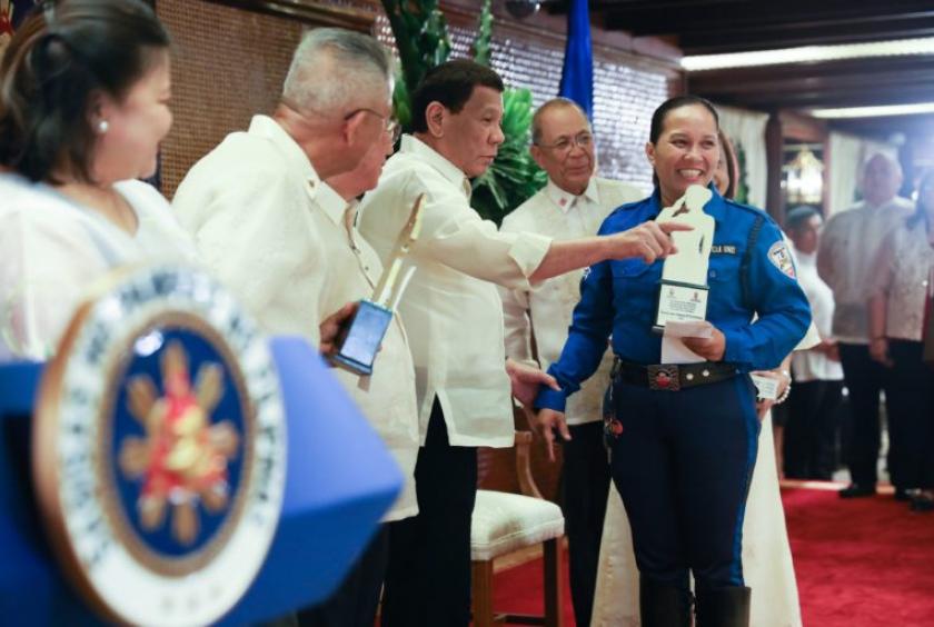 OUTSTANDING WOMEN President Duterte hands an Outstanding Women in Law Enforcement and National Security of the Philippines award to Traffic Aide 1 Rowena Capistrano during ceremonies in Malacañang on Monday night where he said his statements concerning women had been wrongly called sexist or misogynistic. —MALACAÑANG PHOTO