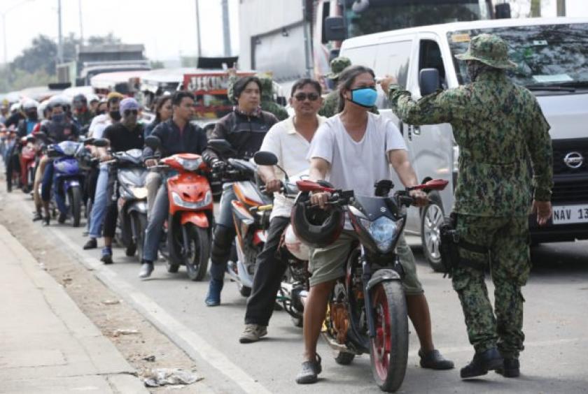 SEALED METROPOLIS Motorcyclists entering Quezon City from San Mateo, Rizal province, are checked for their body temperature at a police checkpoint. (Photo by NIÑO JESUS ORBETA / Philippine Daily Inquirer)