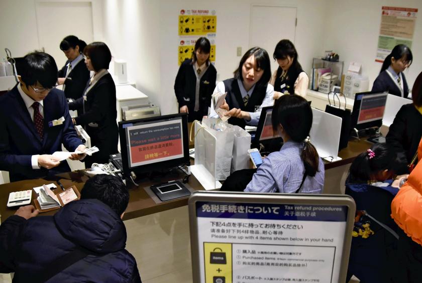 Chinese tourists and other people go through tax-exemption procedures at a counter in the Shinjuku store of Odakyu Department Store Co. in Tokyo on Friday. 