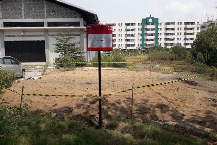A warning sign is placed at a mound suspected to be filled with hazardous and toxic (B3) waste in Marunda, North Jakarta on Jan. 9. (kompas.com/Ardito Ramadhan D)