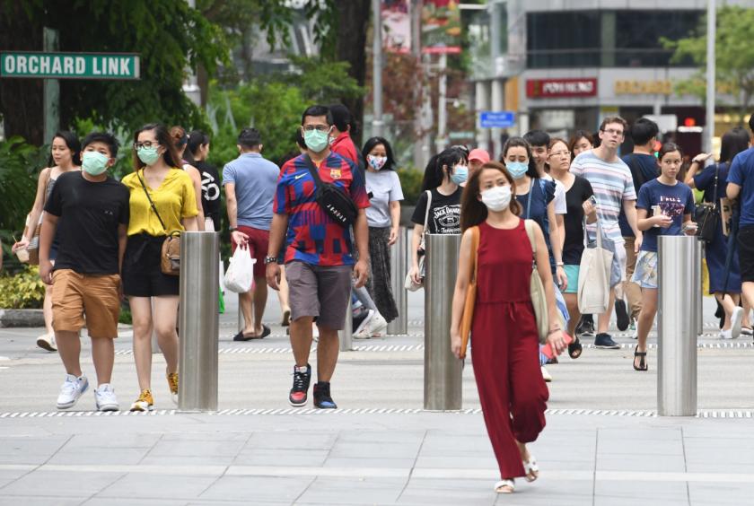 People wear facemasks to try to halt the spread of the COVID-19 coronavirus as they walk through a shopping district on Orchard Road in Singapore on April 5, 2020. Singapore will likely propose a new protocol that would allow for a cross-border movement of people once the COVID-19 pandemic shows a downward trajectory. (AFP/Roslan Rahman) 
