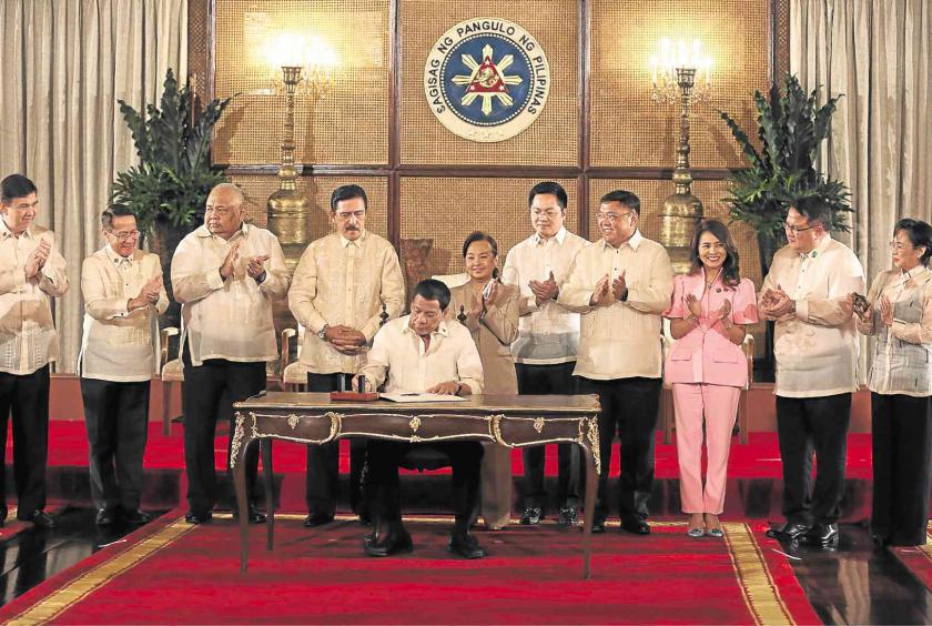 Senate President Vicente Sotto III, Speaker Gloria Macapagal-Arroyo and other legislators applaud President Duterte as he signs the Universal Health Care Act in Malacañang on Wednesday. —JOAN BONDOC
