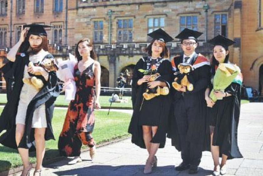 Students from China pose for photos after graduating from a business studies course at the University of Sydney in October 2017. [Photo by William West/For China Daily]