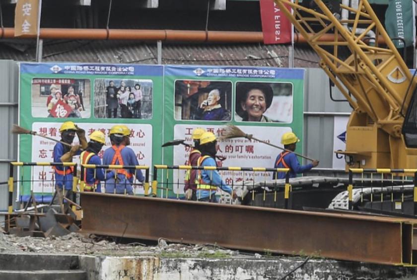 Chinese workers walk past posters showing images of home as they begin the day’s work on the China-funded Binondo-Intramuros Bridge in Manila. —JOAN BONDOC