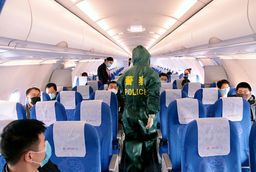 A police officer in protective gear is seen aboard a flight at Putuoshan Airport in Zhoushan, Zhejiang province, on Jan 28, 2020. [Photo by Zou Xunyong/For China Daily]