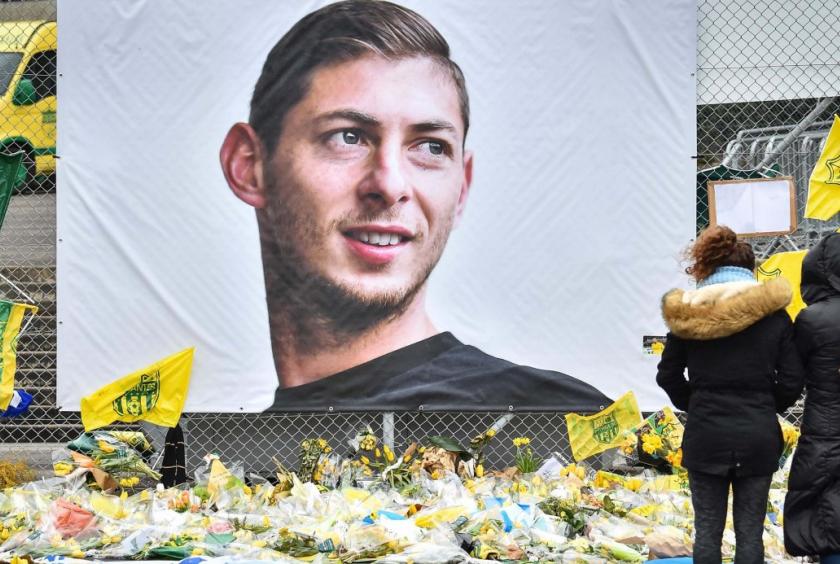 File photo: In this file photo taken on February 8, 2019 people look at yellow flowers displayed in front of the portrait of Argentinian forward Emiliano Sala at the Beauvoir stadium in Nantes. // AFP PHOTO