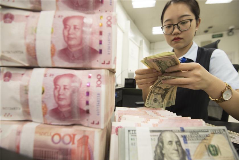 A cashier counts cash at a bank in Nantong, Jiangsu province. [Photo by Xu Jinbo / For China Daily] 
