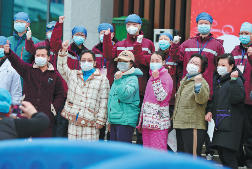 Patients who have recovered from novel coronavirus pneumonia celebrate with medical workers before they are discharged from a temporary hospital in Wuhan, Hubei province, on Tuesday. [Photo by Zhu Xingxin/China Daily] 