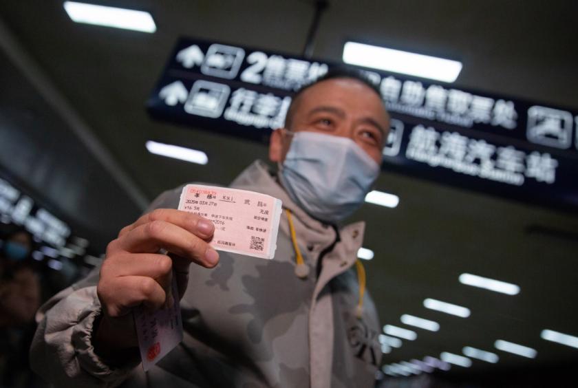 A passenger on train K81 shows his ticket after arriving at Wuchang Railway Station in Wuhan, Central China's Hubei province, on March 28, 2020. Train K81 running from Xi'an to Guangzhou becomes the first passenger train to stop in Wuhan after more than two months of lockdown and transportation suspension in the city. [Photo by Ke Hao/chinadaily.com.cn]