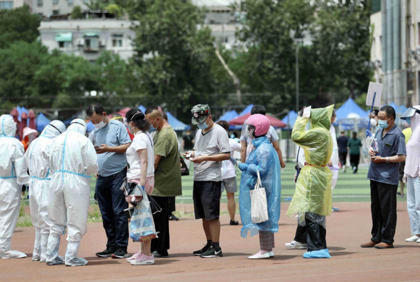 Residents undergo nucleic acid tests for COVID-19 on Monday night at a stadium in Beijing's Xicheng district. [Photo by Zou Hong/China Daily] 