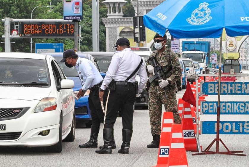 Stricter restriction: Police and army personnel checking a car at a roadblock on the Federal Highway.