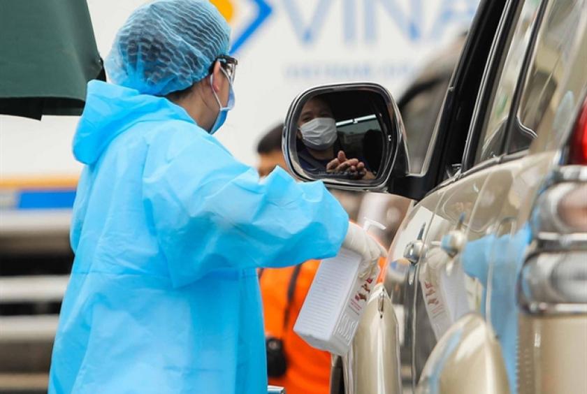 A medical worker sprays a hospital visitor with sanitiser. — Photo nld.com.vn