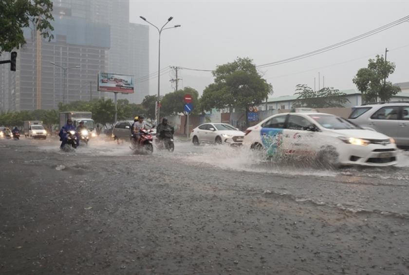 People struggled with floodwaters on Nguyễn Hữu Cảnh Street in Bình Thạnh District of HCM City. Experts at yesterday conference on smart city said that key drivers of the project in HCM City aimed to resolve problems such as unsustainable economic growth, flooding, traffic congestion, pollution, among others. 