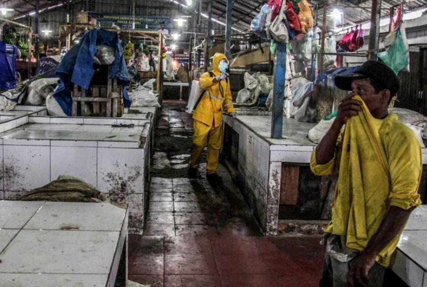 A worker wearing protective gear disinfects a traditional market in Indonesia on March 25, 2020.PHOTO: AFP
