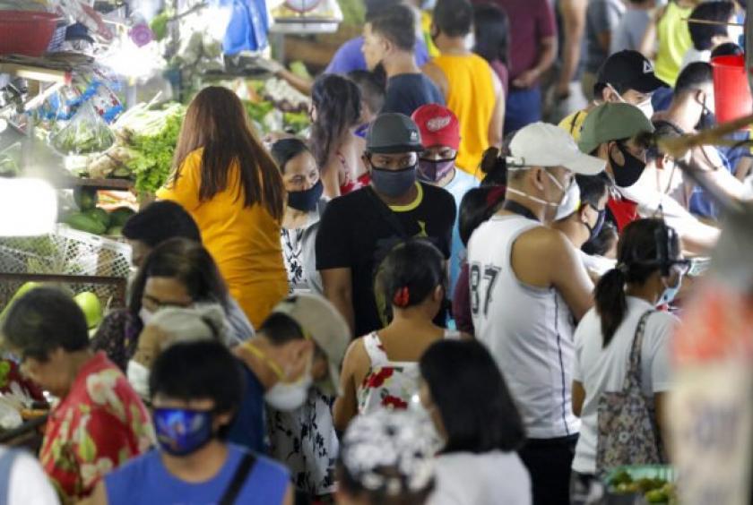 Men wearing protective masks buy food as people rush before the Munoz market closes for its morning business as they cut their operations to four hours a day as part of the enhanced community quarantine to prevent the spread of the new coronavirus in Metro Manila Thursday, March 19, 2020.  (Photo by AARON FAVILA / AP)