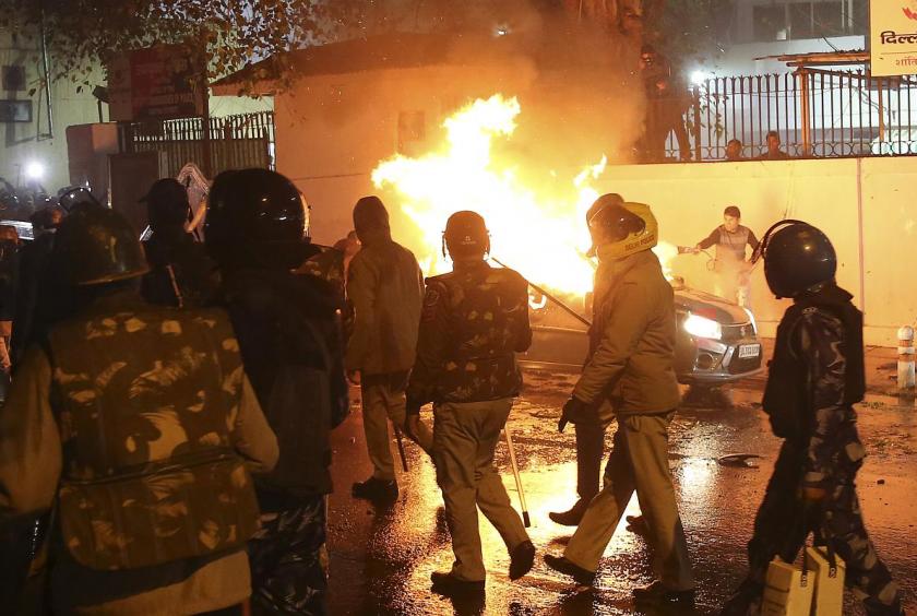 A man tries to put out fire from a burning car during demonstrations against India's new citizenship law in New Delhi on December 20, 2019. - Four new protesters have died in fresh clashes with police in northern India, a medical official said Friday, bringing the death toll to 14 in more than a week of unrest triggered by a contentious citizenship law. (Photo by STR / AFP)