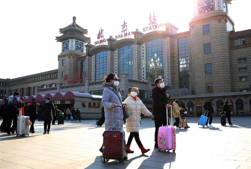 Passengers wearing face masks arrive at the Beijing Railway Station in Beijing on Jan 30, 2020. [Photo by Zou Hong/China Daily]