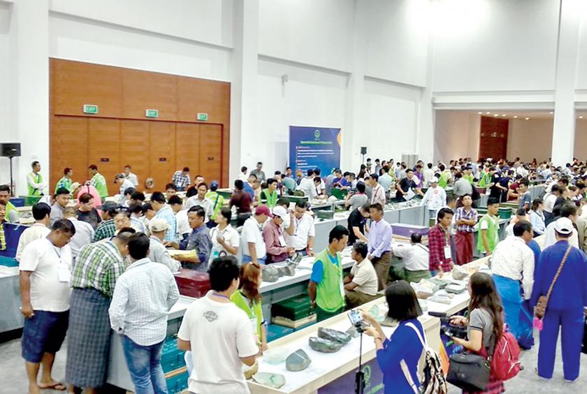 Potential buyers preview uncut jade, jewellery on sale opening day. 