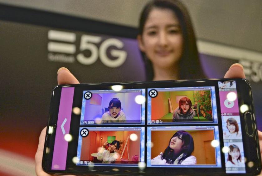 A model holds a smartphone that uses the 5G mobile communication standard.