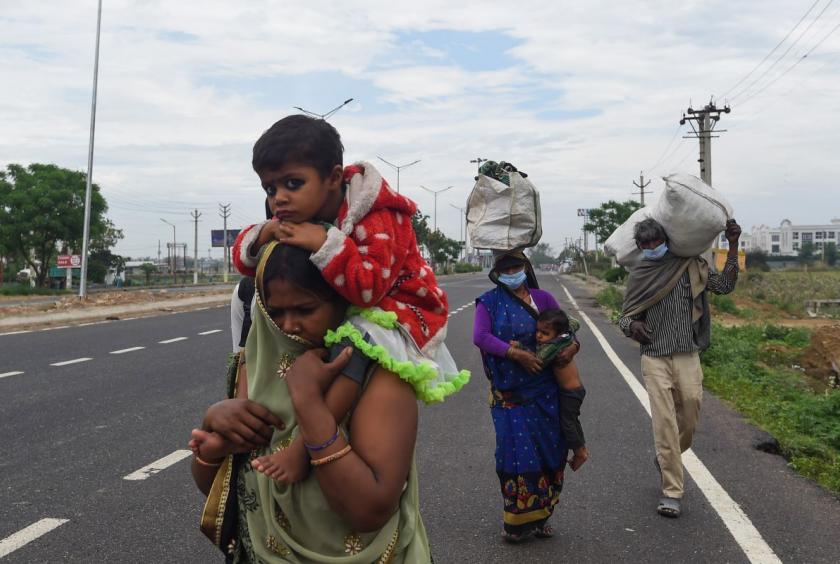 Migrant workers and their family members walk with their belongings on a highway towards Uttar Pradesh as they leave for their villages during a government-imposed nationwide lockdown as a preventive measure against the COVID-19 coronavirus, in Faridabad on March 27, 2020. (Photo by Money SHARMA / AFP)