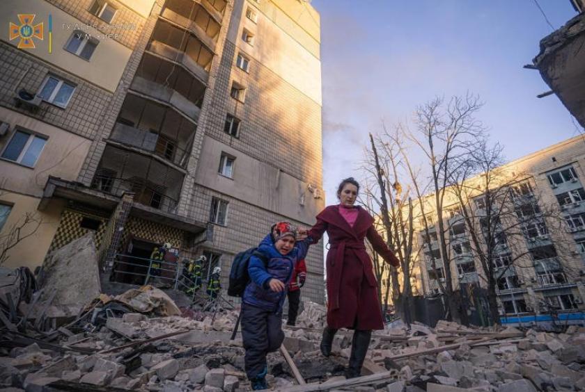 A woman with a child evacuates from a residential building damaged by shelling in Kyiv, on March 16, 2022. PHOTO: REUTERS