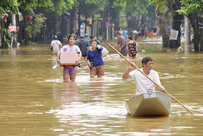 Caption- People carrying belongings wade in a flooded street in Hanoi, Vietnam. PHOTO: AP