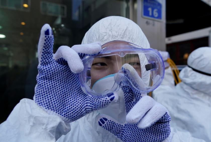 An employee from a disinfection service company wipes moisture from his goggles as he sanitizes a shopping district in Seoul, South Korea, on Thursday. (REUTERS/Kim Hong-Ji)
