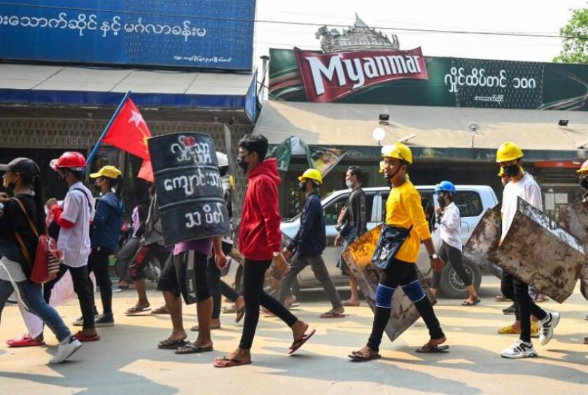 Protesters carry homemade shields as they take part in a demonstration against the military coup in Yangon on March 14, 2021.PHOTO: AFP
