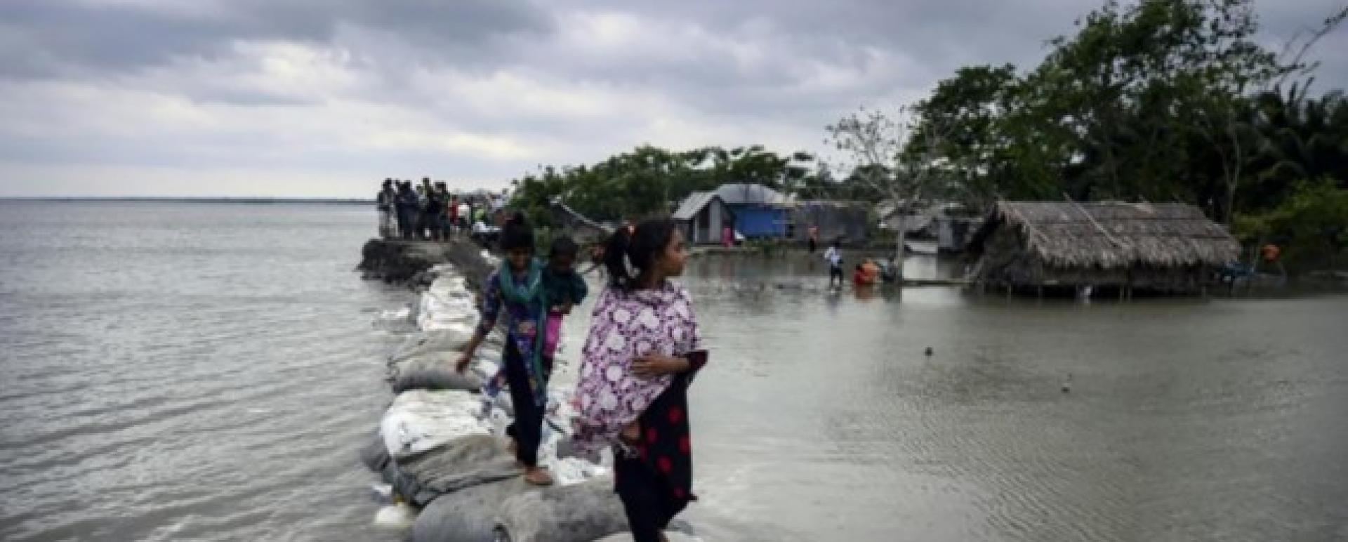 Children walk over the top of a sandbag embankment that was breached by high waters in Khulna on May 4, 2019, after Cyclone Fani reached Bangladesh. Photo: AFP/File
